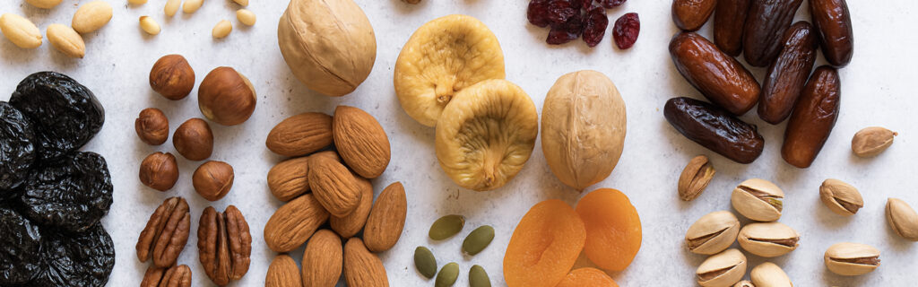 Assorted organic snacks including dried fruits, nuts, and seeds arranged neatly on a light surface, showcasing healthy and natural snack ingredients.