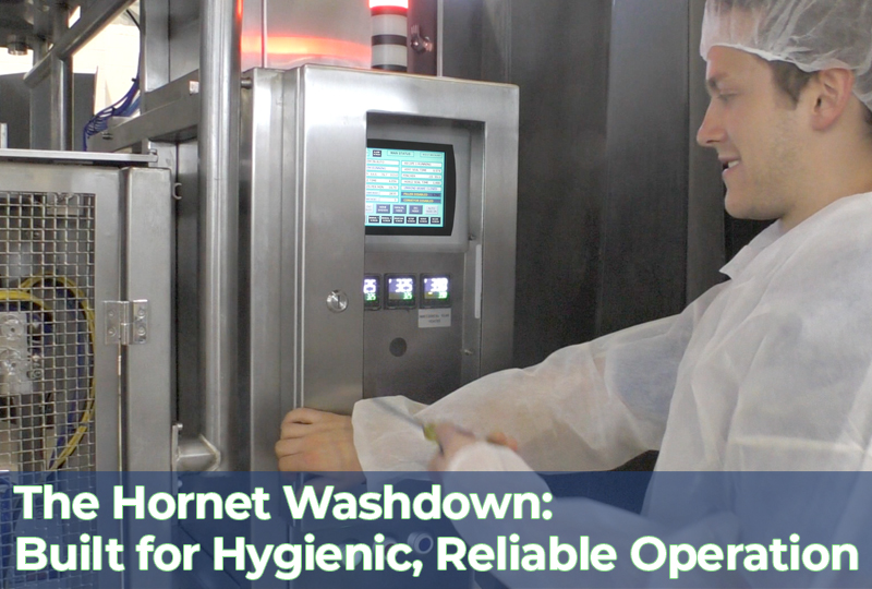 Operator in a cleanroom suit using the control panel of a stainless-steel Hornet Washdown vertical form fill seal (VFFS) machine designed for hygienic frozen food packaging.