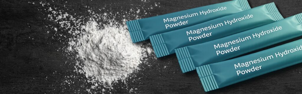 Magnesium hydroxide powder with single-serve stick pack sachets on a dark surface